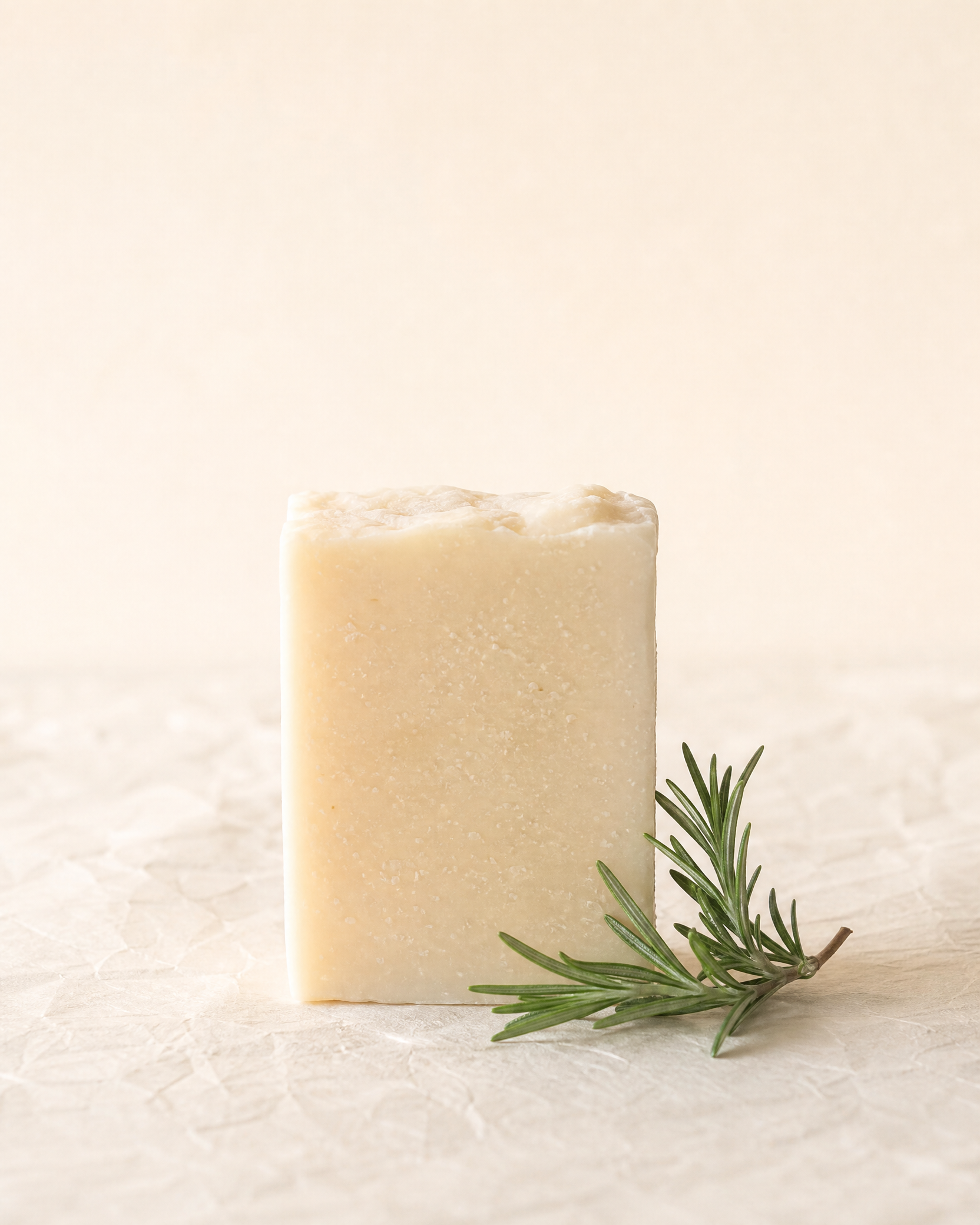 A rosemary soap bar on an ivory paper surface
